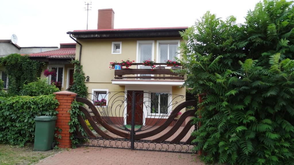 uma cerca em frente a uma casa com uma varanda em Pokoje na Ptasiej em Mikolajki