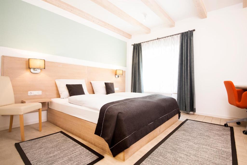 um quarto com uma cama grande e uma cadeira em Altes Eishaus, Hotel & Restaurant em Giessen