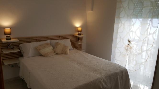1 dormitorio con cama blanca y ventana en La casa di Luvy, en Ostuni