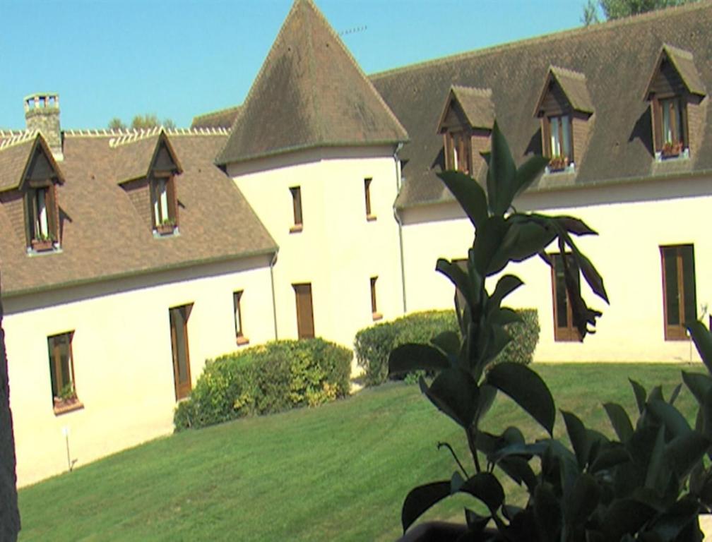 a large white building with windows on a green field at La Tour des Plantes in Moncé-en-Belin