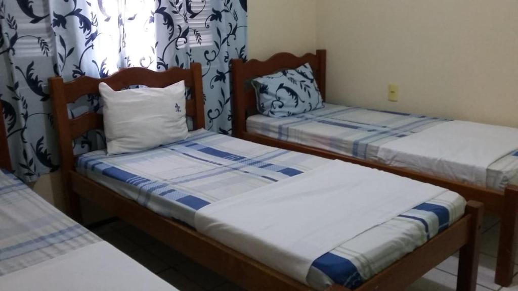 two twin beds in a room with curtains at Pousada Recanto das Férias in Fortaleza
