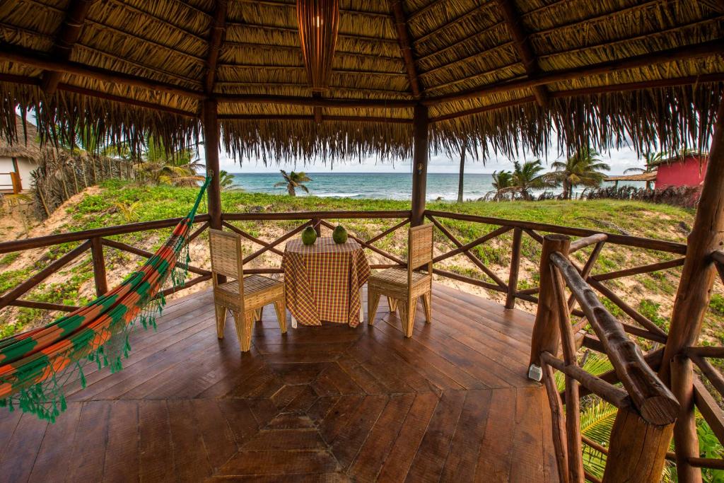 un porche con mesa y sillas en la playa en Paradise Beach House en Imbassai