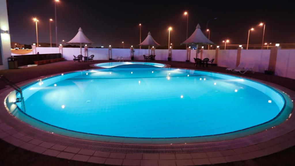 a large blue swimming pool at night at Remas Hotel Suites - Al Khoudh, Seeb, Muscat in Seeb