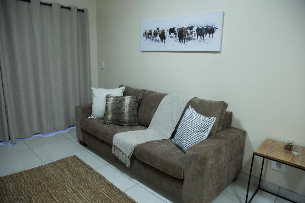 a living room with a couch and a picture on the wall at The Living Collective Apartments in Pietermaritzburg