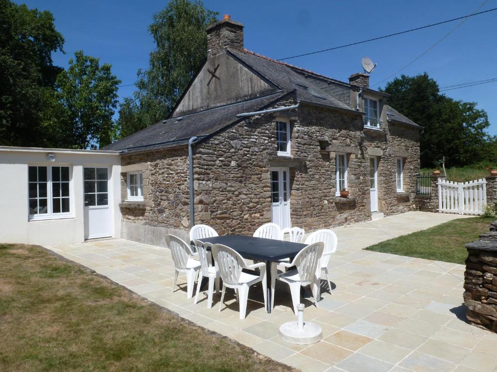 a table and chairs in front of a stone building at Gite Ker Maria Gite Ker Louis Piscine in Saint-Gravé