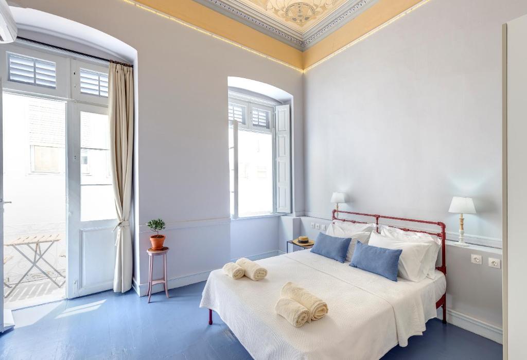 a white bedroom with a large bed with blue pillows at Homey in Ermoupoli
