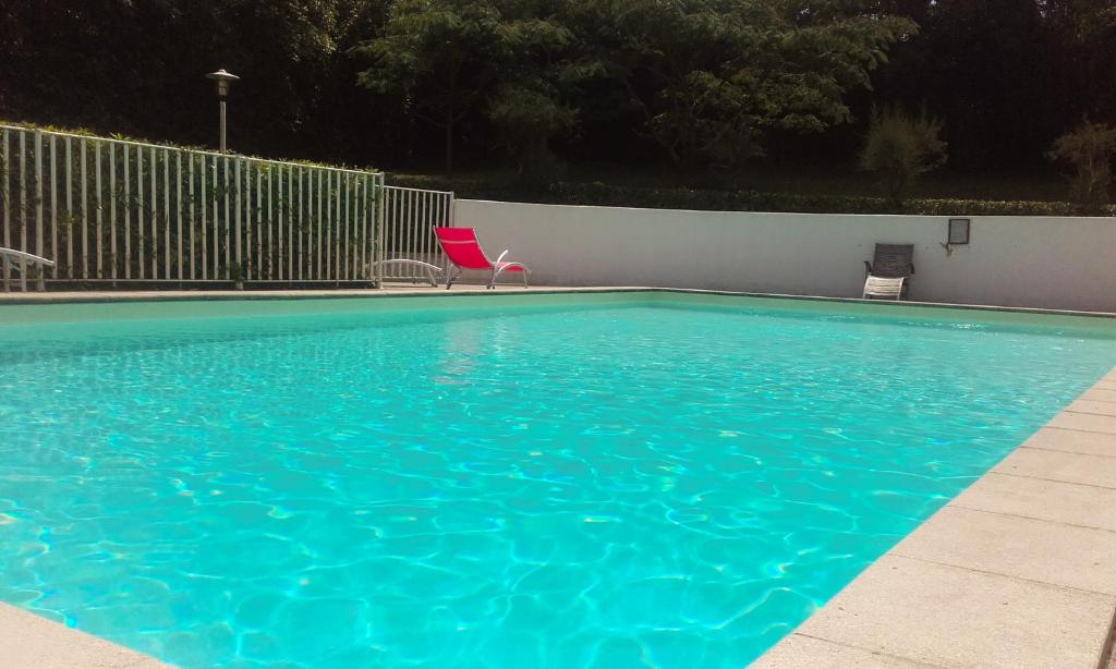 a blue swimming pool with a red chair in it at Hotel Villa Catarie in Guéthary