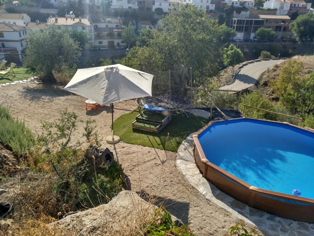 an umbrella sitting next to a swimming pool at Casa La Liebrecilla in Ríogordo