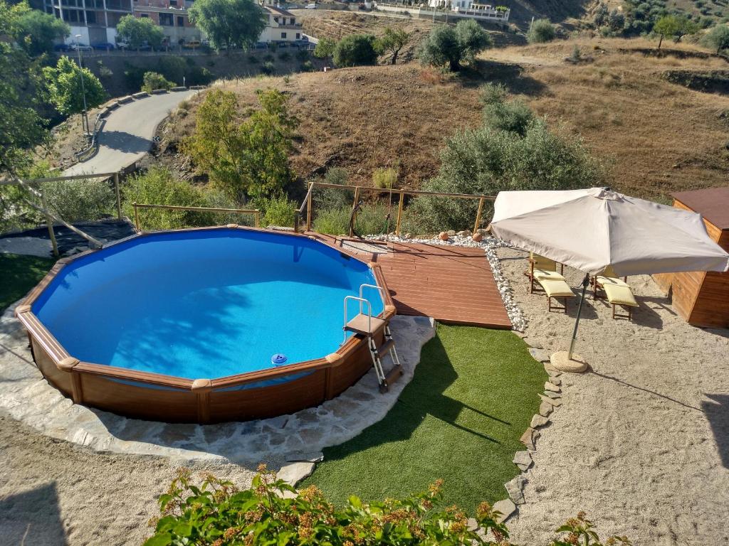 una grande piscina con ombrellone e alcune sedie di Casa La Liebrecilla a Ríogordo