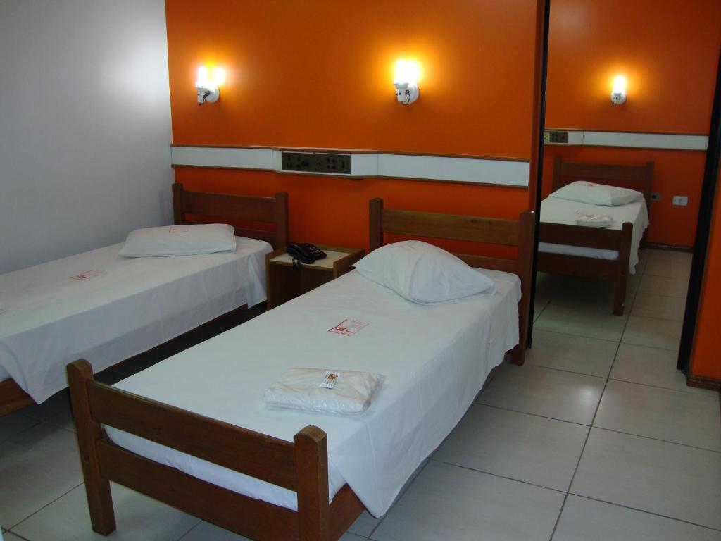 two beds in a room with orange walls at Hotel - Pousada do Arco Iris in Osasco