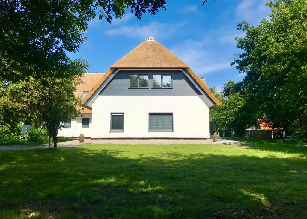 a large white house with a thatched roof at The island life Texel - Wellness in De Koog