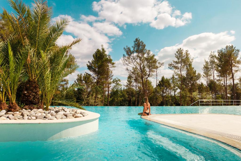 a woman sitting on the edge of a swimming pool at Mobile Homes Camping Santa Marina, Lanterna in Poreč