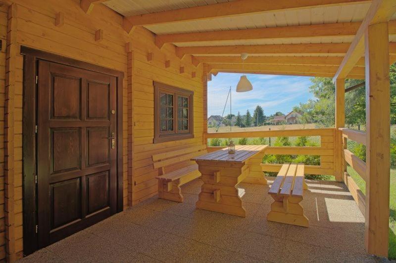 una veranda di una cabina in legno con panchina e porta di Domki na 102 a Junoszyno