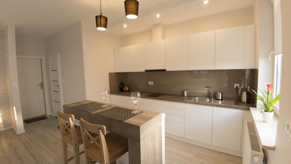 a kitchen with white cabinets and a table with chairs at Apartament Termalny Komfort 8.2 in Uniejow