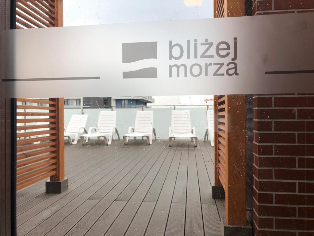 eine Gruppe weißer Stühle auf einem Deck in der Unterkunft Apartament Bliżej Morza in Kołobrzeg