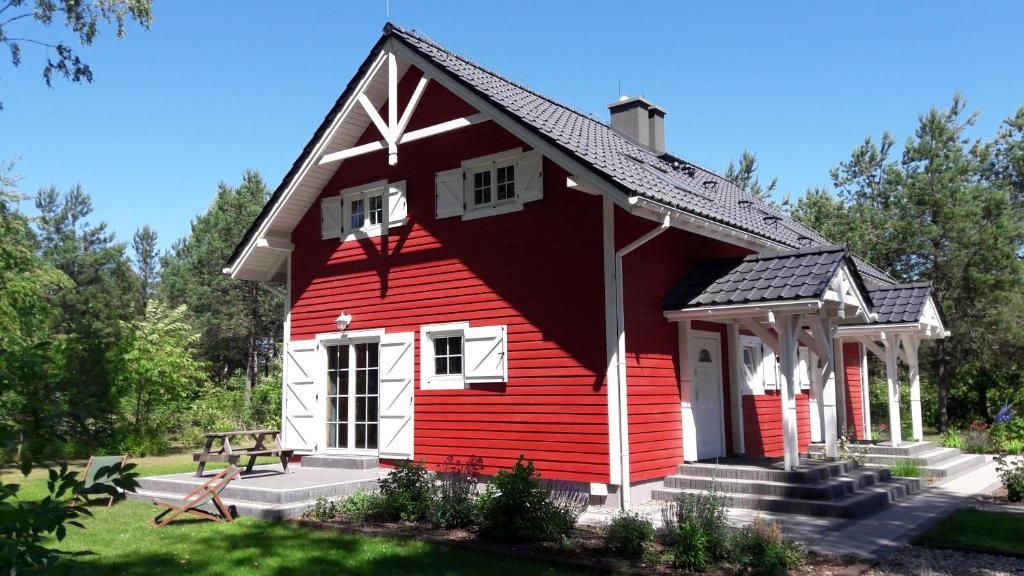 a red and white house with a bench in front at Apartamenty Jezioro i Las Mazury in Powałczyn