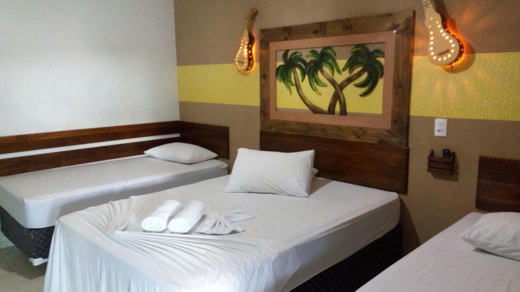 two beds in a room with white towels on them at Pousada Rota das Águas in Nobres