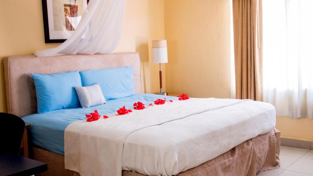 自由鎮的住宿－The Jam Lodge，一间卧室配有一张红色鲜花的大床
