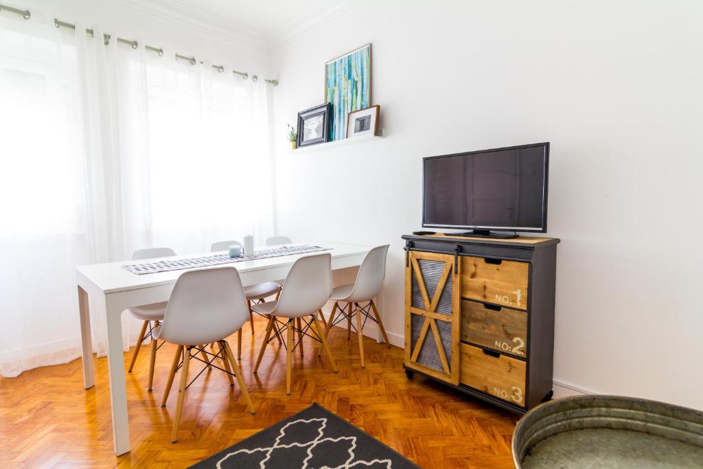 une salle à manger avec une table, des chaises et une télévision dans l'établissement Avenidas Cozy Apartment, à Lisbonne