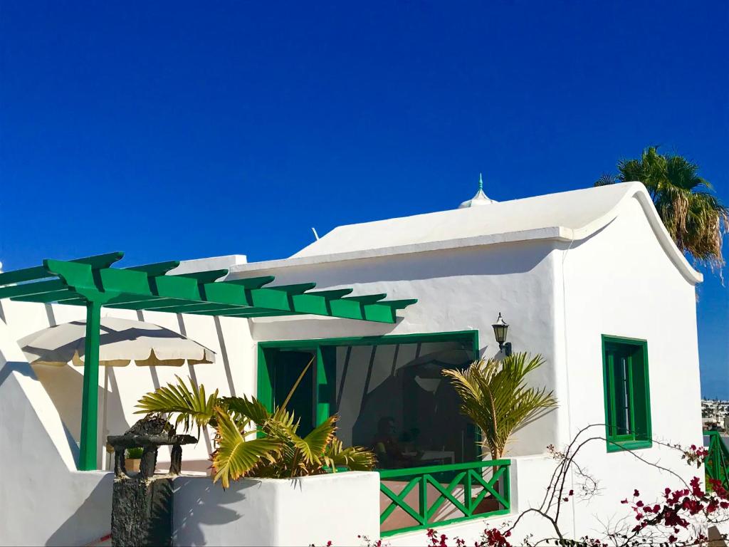 a white house with a green pergola at Blue Sky in Puerto del Carmen
