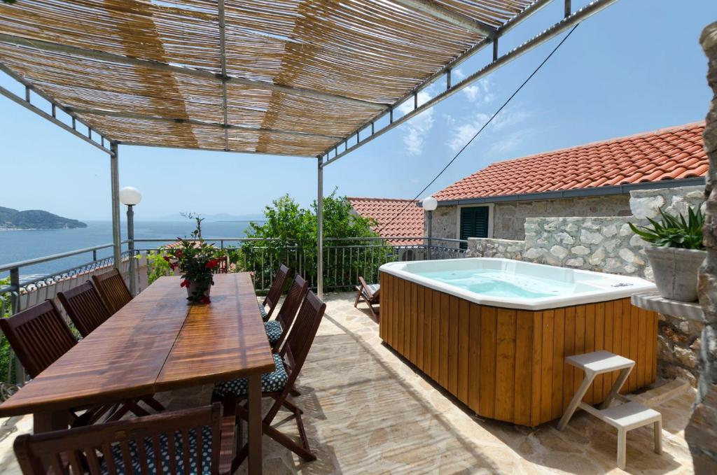 un patio con bañera de hidromasaje, mesa y sillas en House Jasna, en Igrane