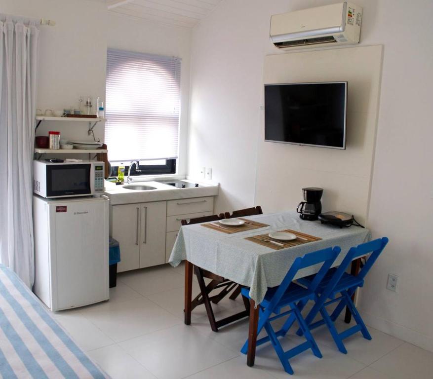 eine kleine Küche mit einem Tisch und blauen Stühlen in der Unterkunft Apartamento Centro Búzios in Búzios