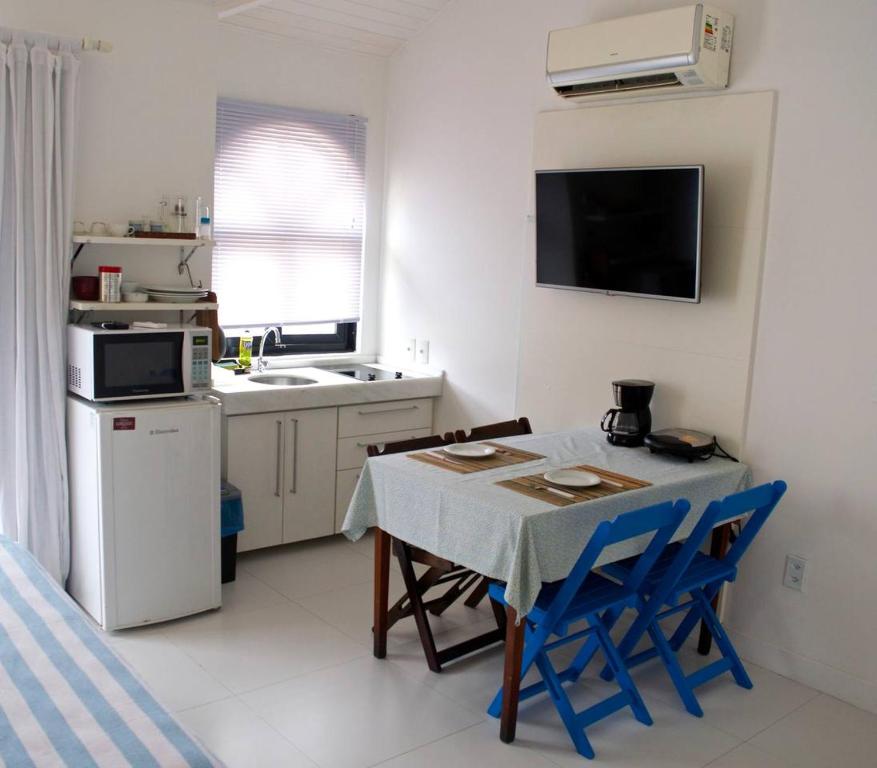 una pequeña cocina con mesa y sillas azules en Apartamento Centro Búzios, en Búzios