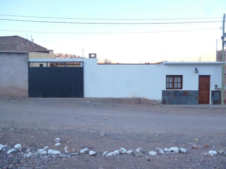 Un edificio blanco con muchas rocas delante. en Cabana Mirador Sumajpacha, en Tilcara