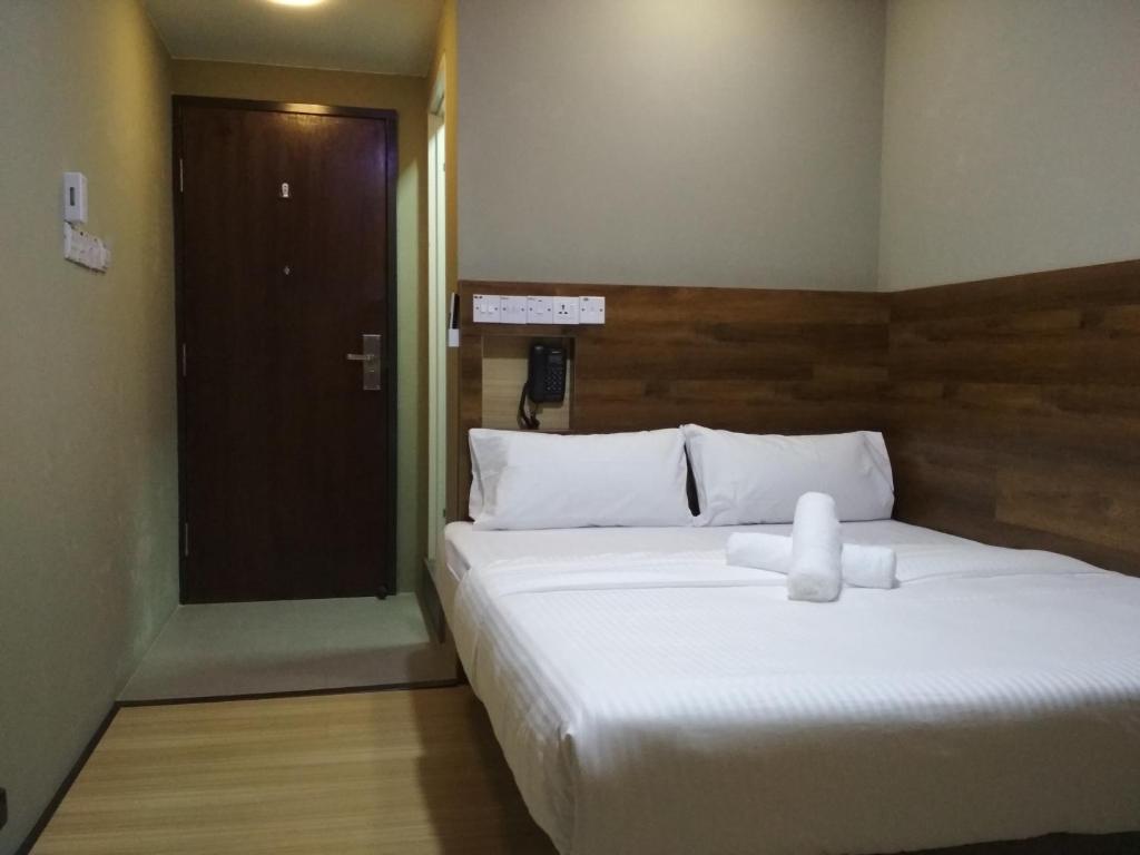 Qing Yun Rest House Gadong, Brunei Darussalam في بندر سيري بيغاوان: غرفة نوم بسرير ابيض كبير وباب