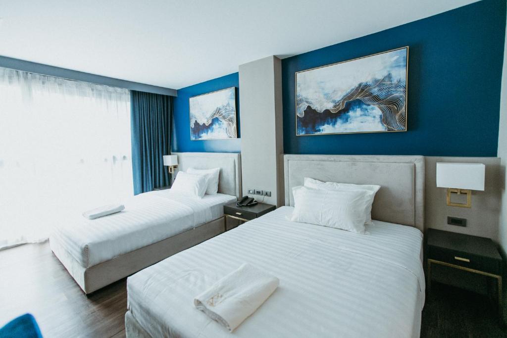 ドゥマゲテにあるPVL Suitesのブルーウォールのホテルルーム内のベッド2台