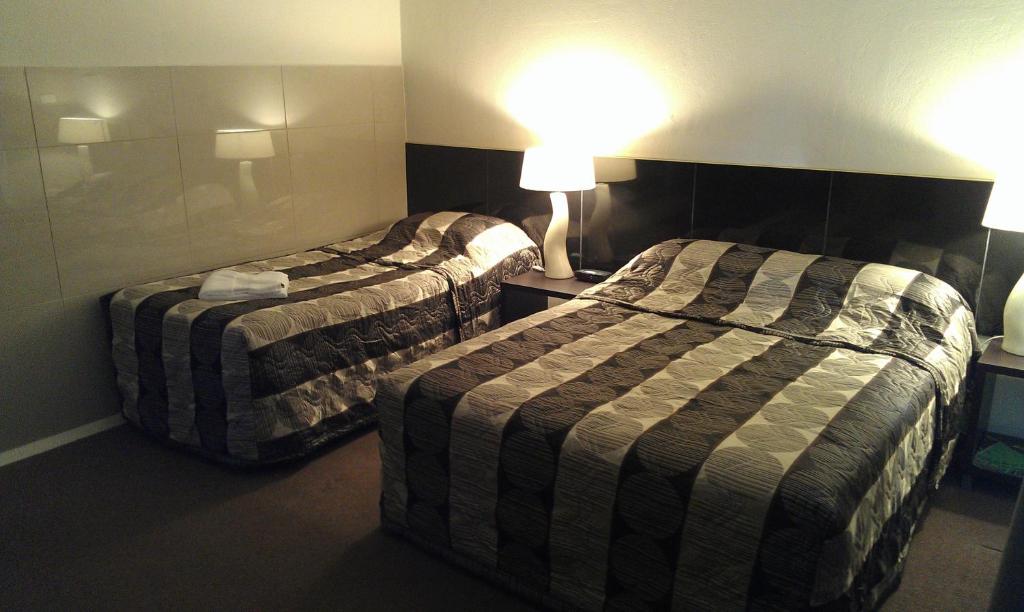 een hotelkamer met 2 bedden en een lamp bij Avalon Motel in Mount Gambier
