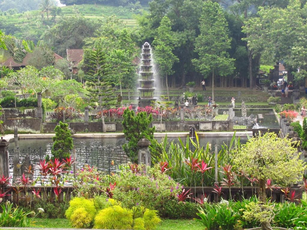 einen Brunnen in einem Garten mit Blumen und einem Teich in der Unterkunft Dhangin Taman in Tirtagangga