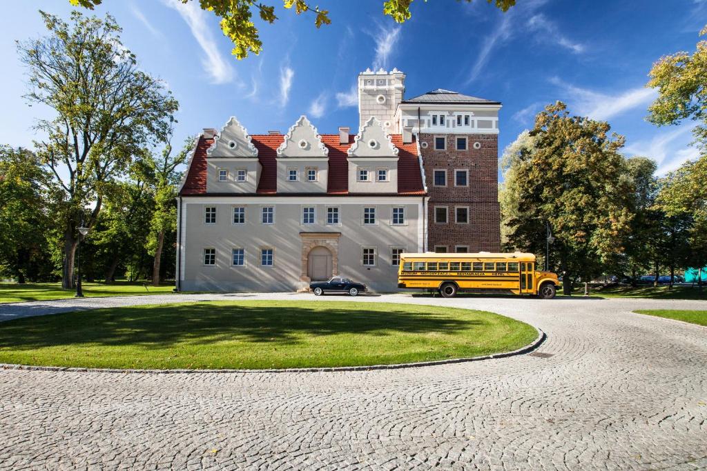 żółty autobus szkolny zaparkowany przed budynkiem w obiekcie Zamek Topacz we Wrocławiu