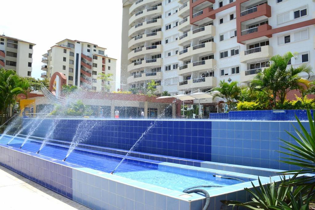 a swimming pool with a fountain in front of buildings at Playa Almendro Resort in Tonsupa