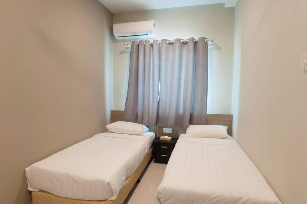 two beds in a small room with a window at C Residence Labuan in Labuan