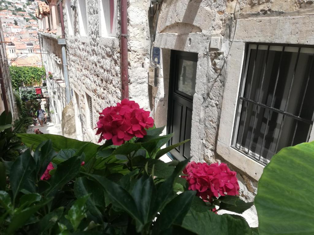 un edificio con flores rosas frente a una ventana en Apartment Dubrovnik Center en Dubrovnik