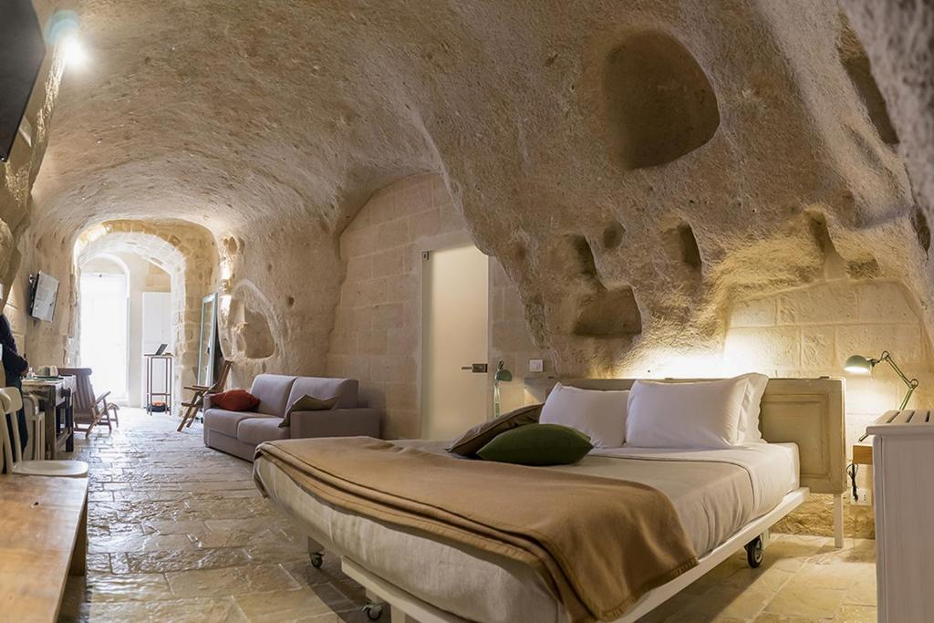 1 dormitorio con 1 cama grande en una pared de piedra en Thymus Residence nei Sassi, en Matera