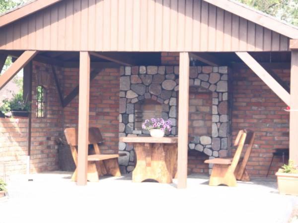 a patio with two chairs and a table and a stone wall at Apartamenty Nadmorskie in Rewa
