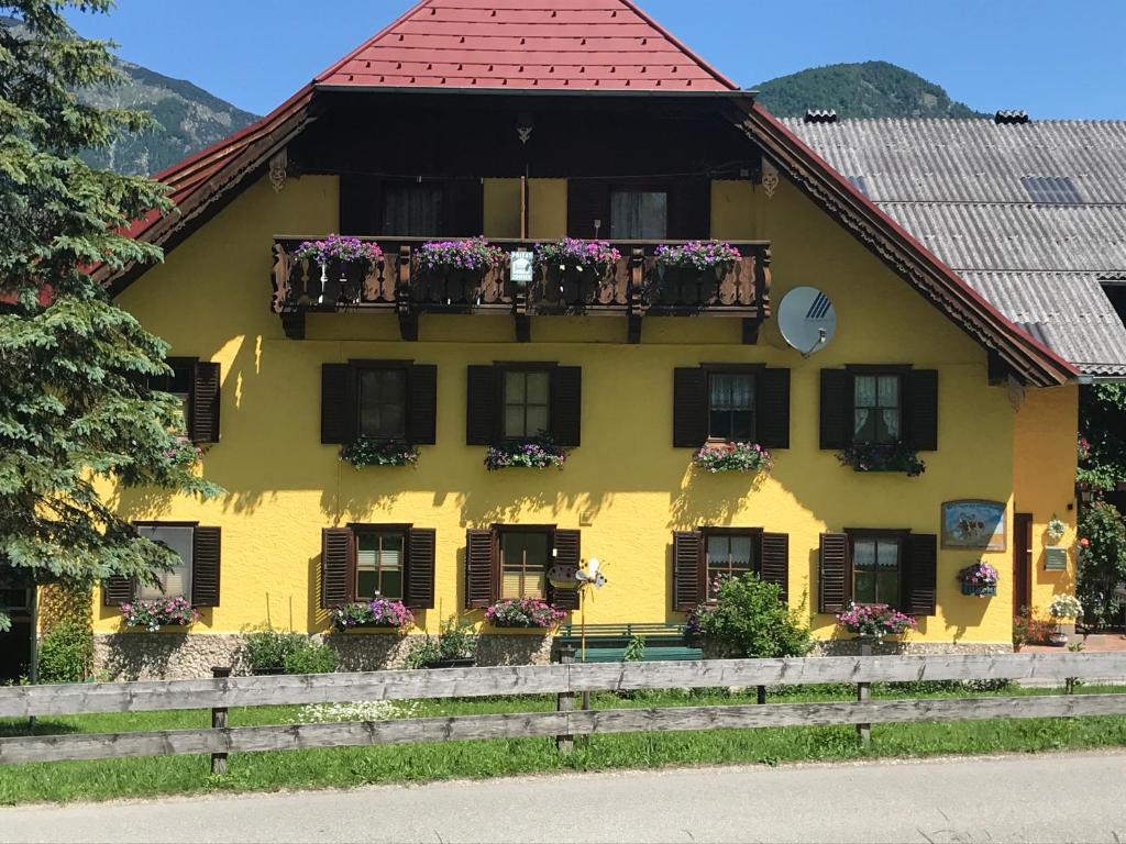 una casa amarilla con flores en las ventanas en Wagnermoosgut en Bad Ischl