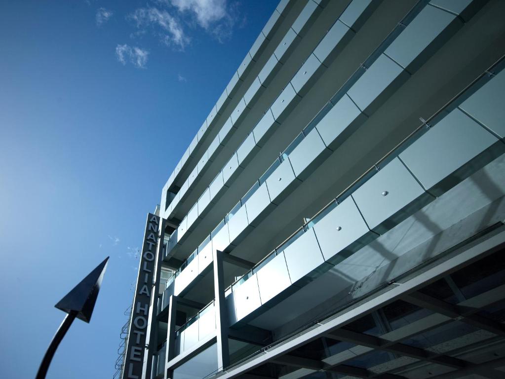 un edificio de cristal alto con una bandera delante de él en Anatolia Hotel Komotini, en Komotiní