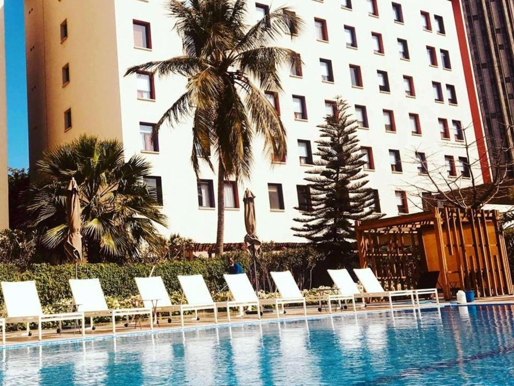 a row of white lounge chairs next to a building at Ibis Dakar in Dakar