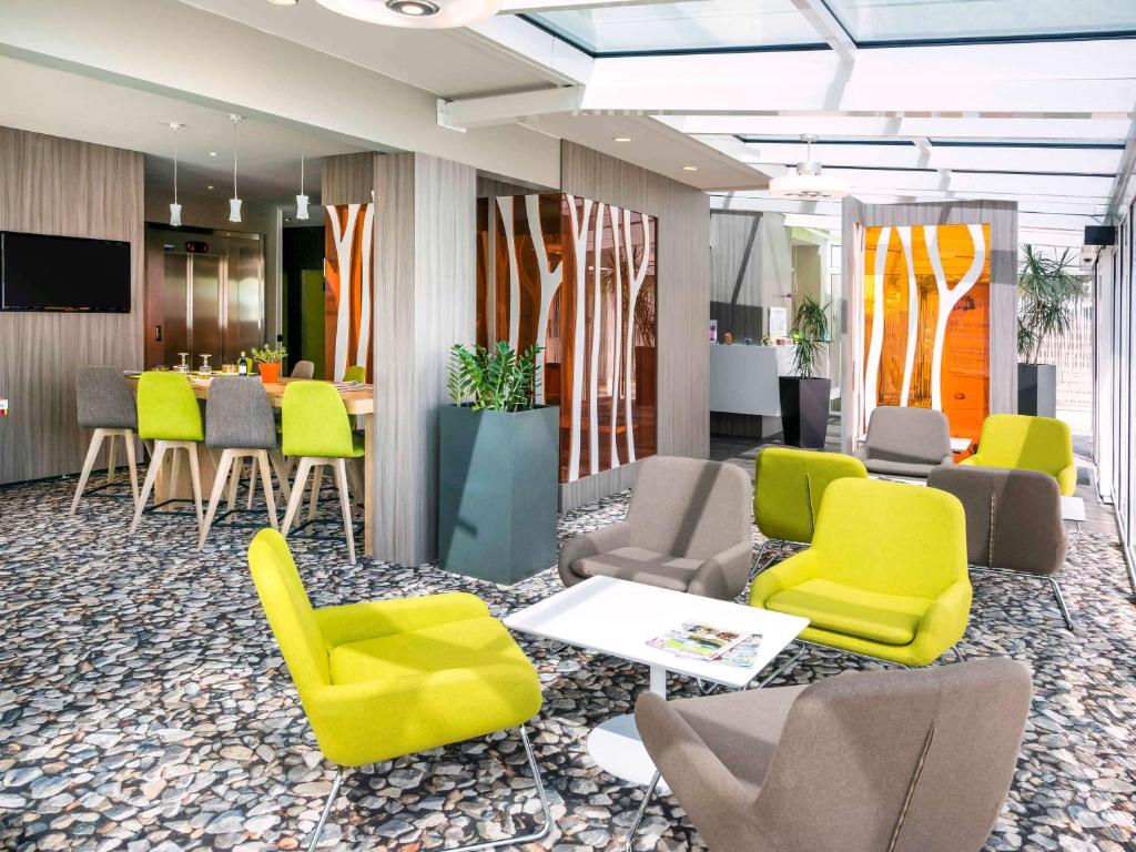 um átrio com cadeiras amarelas e cinzentas e uma mesa em Ibis Styles Annemasse Genève em Ambilly