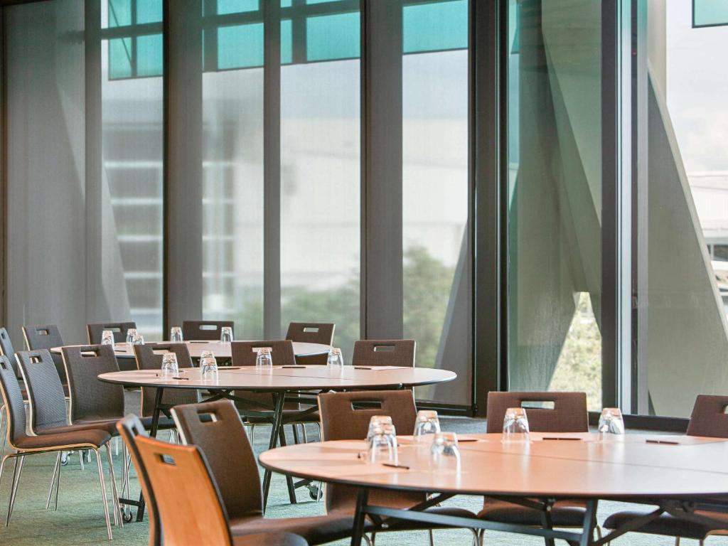 a row of tables and chairs in a room with windows at Novotel Auckland Airport in Auckland