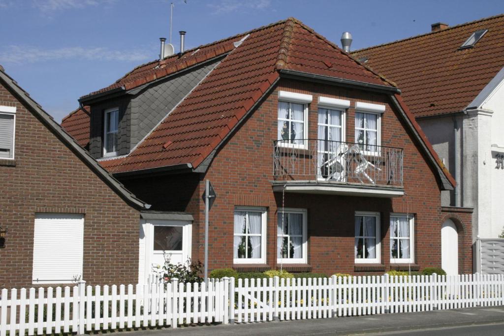 une maison en briques rouges avec une clôture blanche dans l'établissement Haus Schleusenblick, à Carolinensiel