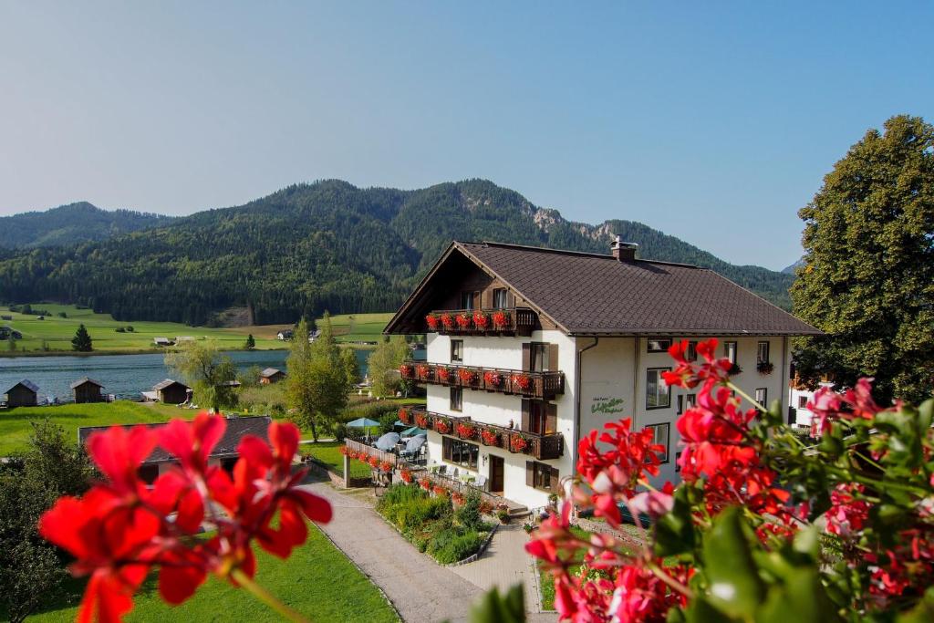 a building with red flowers in front of it at Hotel Lipeter & Bergheimat in Weissensee