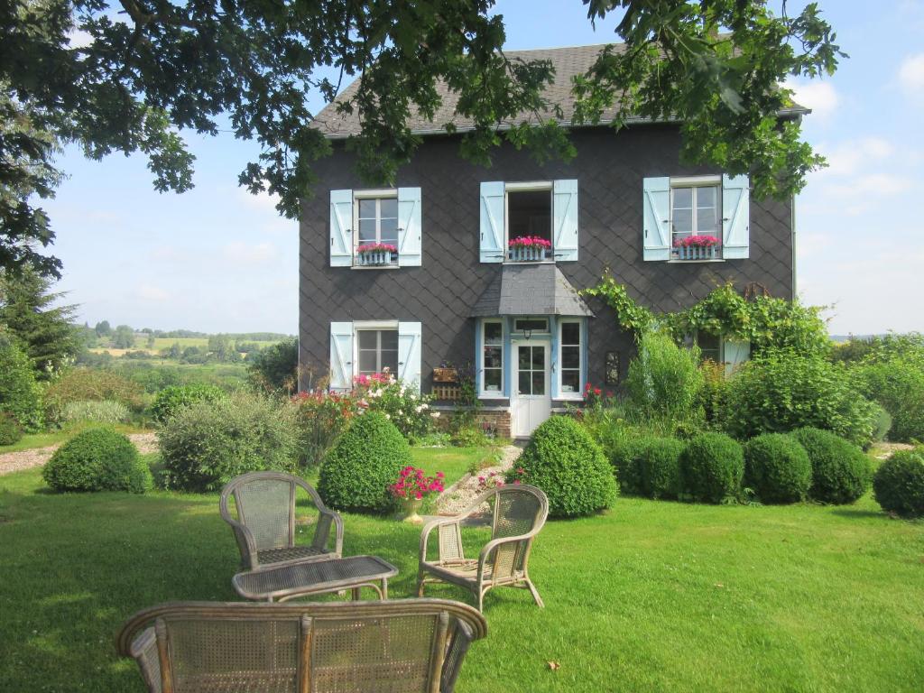 a house with chairs sitting in the yard at Le Clos Lauradière in Cormeilles