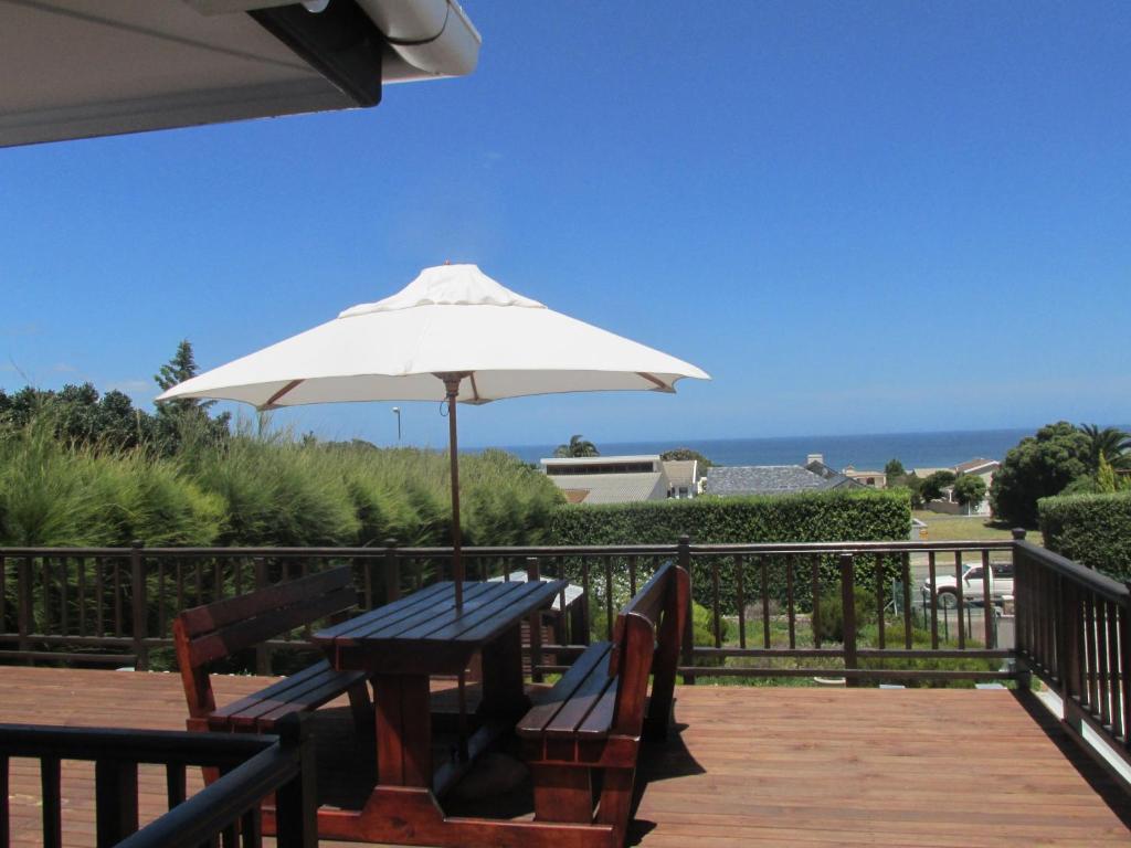 a picnic table with an umbrella on a deck at Casa Del Mar in Hermanus
