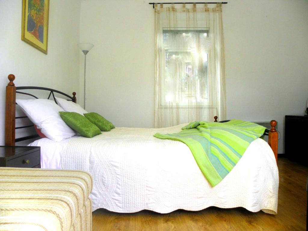 Un dormitorio con una cama con almohadas verdes y una ventana en Pansion Sibenik, en Šibenik