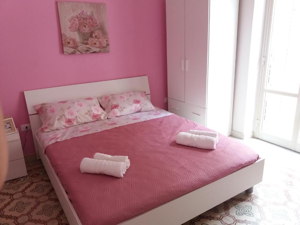 una camera rosa con un letto con due cuscini sopra di A casa di Alba a Marsala