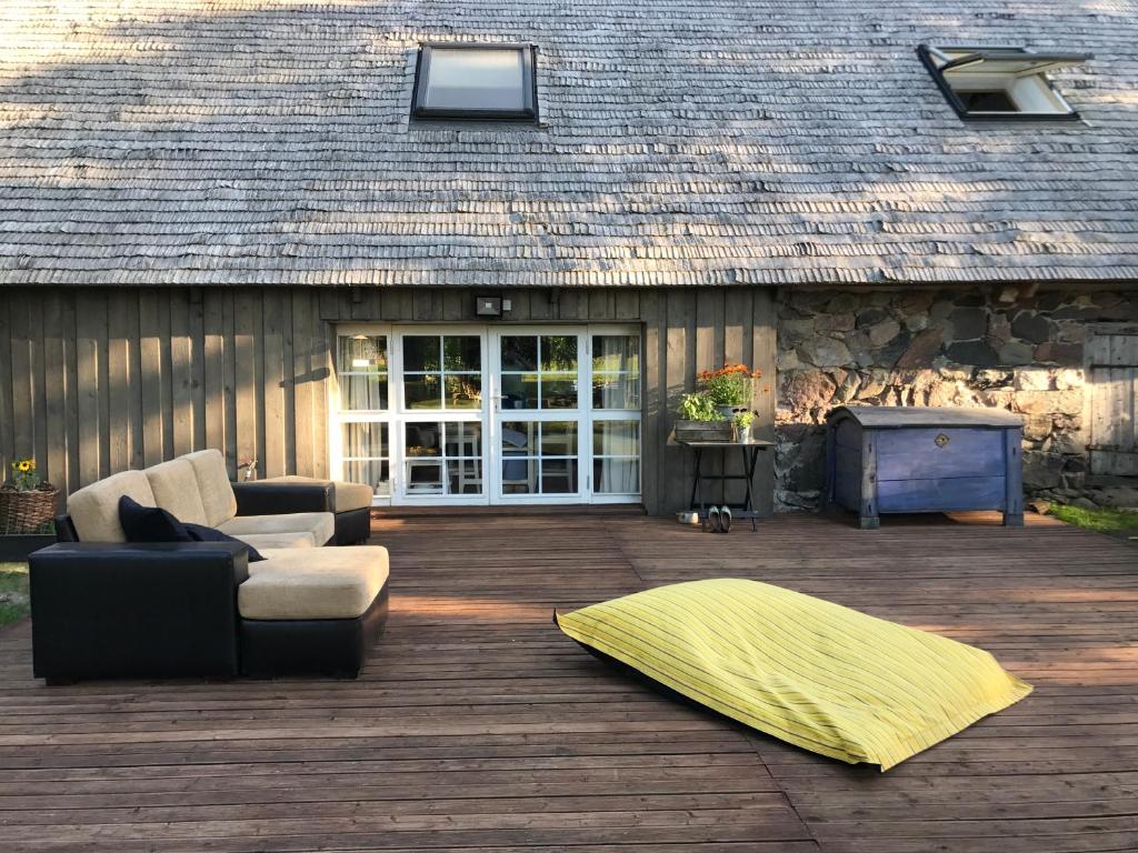 a patio with a couch and a rug on a wooden deck at Jaagu-Mihkli Muhu Island in Ridasi